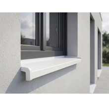 Biely vonkajší parapet namontovaný na svetlej fasáde pod tmavým okenným rámom.