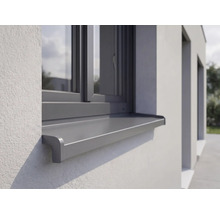 Vonkajší hliníkový parapet inštalovaný na omietnutej fasáde pod oknom.