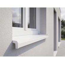 Vonkajší okenný parapet biely z plastu pod oknom na svetlej omietnutej fasáde.