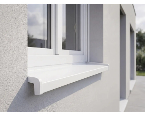 Vonkajší okenný parapet biely z plastu pod oknom na svetlej omietnutej fasáde.