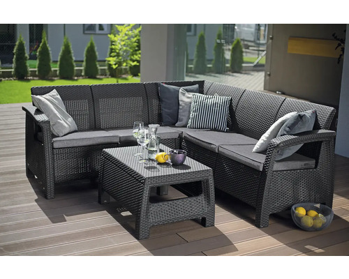 Záhradný lounge set z antracitovej rohovej pohovky v ratanovom vzhľade a nízkeho stolíka na drevenej terase.