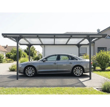 Samostatne stojaci moderný prístrešok pre auto s kovovým rámom a priesvitnými strešnými panelmi, chrániaci auto na príjazdovej ceste.