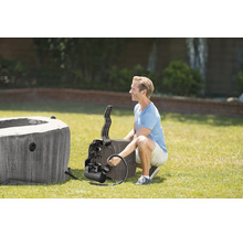 Muž inštaluje čerpadlo k nafukovacej vírivke v záhrade na trávniku.