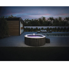 Nafukovacia vírivka Intex s kamenným dekorom na modernej terase s bazénom a záhradným nábytkom za súmraku.