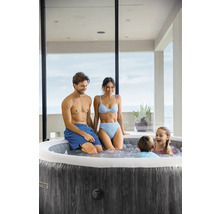 Rodina relaxuje v okrúhlej nafukovacej vírivke s tmavým dreveným dekorom na svetlej terase.