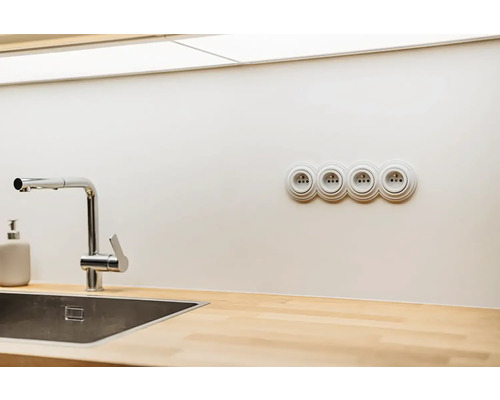 Moderná kuchyňa s nerezovým drezom, chrómovou batériou, drevenou pracovnou doskou a štvornásobnou zásuvkou.