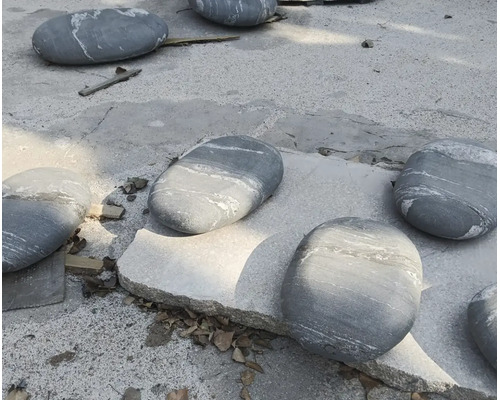 Veľké ploché záhradné kamene v sivej farbe s bielym žilkovaním.
