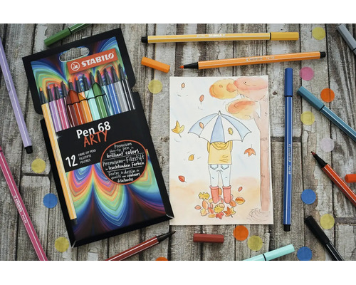 Sada 12 fixiek STABILO Pen 68 Arty s jesennou kresbou a rozhádzanými perami na drevenom podklade.
