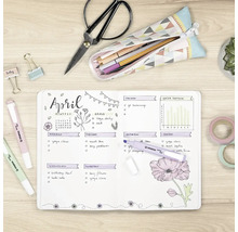 Pohľad zhora na svetlý, usporiadaný písací stôl s otvoreným bullet journalom, zvýrazňovačmi Stabilo Swing Cool, nožnicami a papiernictvom.