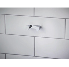 Dvojitý kúpeľňový háčik Hansgrohe z chrómovaného kovu, namontovaný na dláždenej stene.