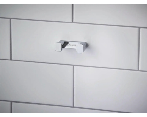 Dvojitý kúpeľňový háčik Hansgrohe z chrómovaného kovu, namontovaný na dláždenej stene.