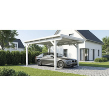 Biely drevený prístrešok pre auto s plochou strechou pred moderným bielym domom s parkujúcim autom na dláždenej príjazdovej ceste.