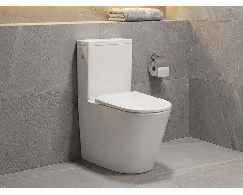 Moderné stojace keramické WC s nádržkou v kúpeľni so sivými obkladmi v dekore prírodného kameňa.
