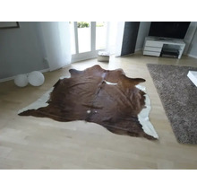 Prírodne tvarovaný koberec z hovädzej kože v svetlej, moderne zariadenej obývacej izbe so svetlou parketovou podlahou.