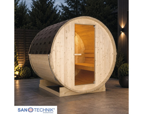 Sudová sauna Sanotechnik z dreva na terase za súmraku s presklenými dverami, vnútorným osvetlením a šindľom. Sanotechnik Logo.