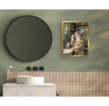 Kúpeľňa s bielym umývadlom na dosku, čiernymi nástennými batériami, veľkým okrúhlym zrkadlom a obrazom mačky v zlatom ráme.