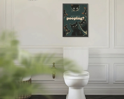 Zarámovaný obraz na stenu s čiernymi mačkami a textom are you pooping? nad bielou toaletou v kúpeľni.