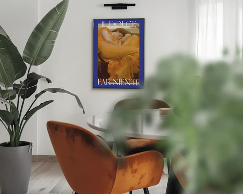 Moderný interiér so zarámovaným plagátom s textom Il Dolce Far Niente na stene, veľkou rastlinou, zamatovým kreslom a stolom.