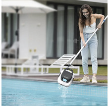 Zena vytahuje bazénový robot Aiper Scuba SE z bazéna pomocou teleskopickej tyce v záhrade.