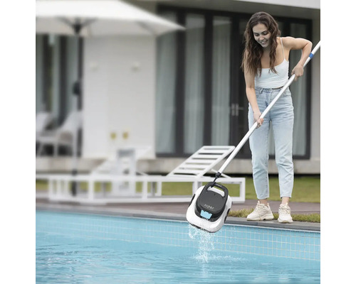 Zena vytahuje bazénový robot Aiper Scuba SE z bazéna pomocou teleskopickej tyce v záhrade.