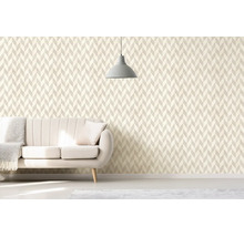 Obývacia izba s geometrickou tapetou v štýle chevron, svetlou čalúnenou pohovkou a minimalistickým závesným svietidlom.