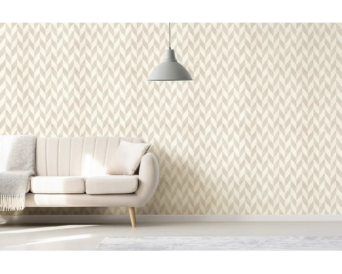 Obývacia izba s geometrickou tapetou v štýle chevron, svetlou čalúnenou pohovkou a minimalistickým závesným svietidlom.