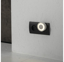 Okrúhle nočné LED svetlo s teplým svetelným krúžkom zapojené do dvojitej zásuvky na štruktúrovanej stene.