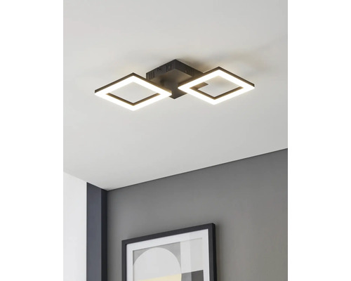 Moderné stropné LED svietidlo s dvoma štvorcovými čiernymi rámami, namontované na bielom strope nad sivou stenou s rámovaným obrazom.
