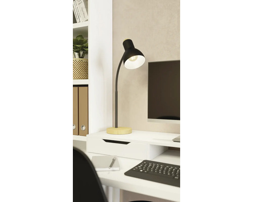 Moderná stolná lampa z čierneho kovu s dreveným podstavcom na bielom písacom stole vo svetlom, organizovanom pracovnom priestore.