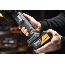 Ruky vkladajú akumulátor DeWalt 18 Voltov 5 Ampérhodín McLaren Special Edition do akumulátorového náradia.