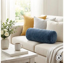 Rebrovaný vankúš valcového tvaru v modrej farbe na svetlej pohovke, doplnený dekoratívnymi vankúšmi, vázou s kvetmi a šálkou kávy. (Image AI modified or generated)