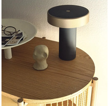 Moderná nabíjacia lampa na okrúhlom drevenom odkladacom stolíku s dekoratívnymi predmetmi.