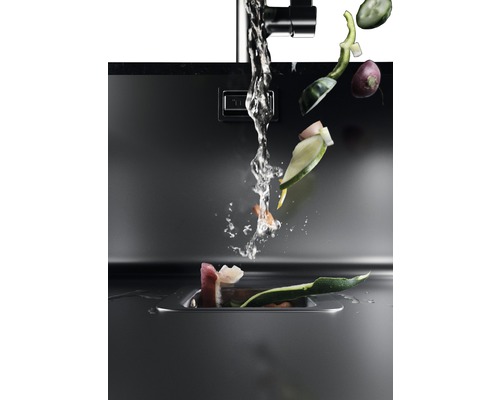 Kuchynský drez s tečúcou vodou a zeleninovým odpadom