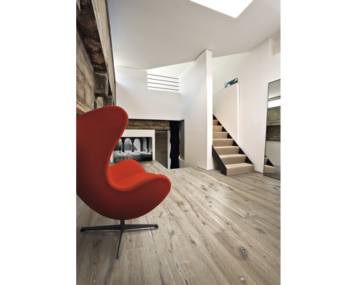 Obývacia izba s drevenou podlahou, schodiskom a kreslom