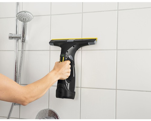 Ruka používa vysávač okien na obkladačky v kúpeľni