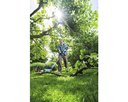 Muž strihá konáre s vyvetvovacou pílou v záhrade.