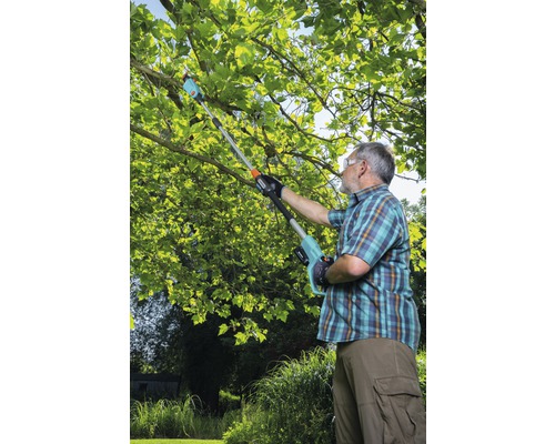 Muž strihá konáre stromov pomocou akumulátorovej prerezávacej píly