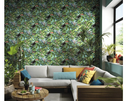 Obývacia izba s tapetou so vzorom tropického tukana, sivou rohovou pohovkou a izbovými rastlinami pre svetlé a usporiadané prostredie.