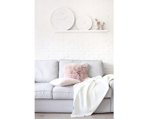 Obývacia izba s pohovkou, vankúšmi, dekou a dvoma hodinami na stene