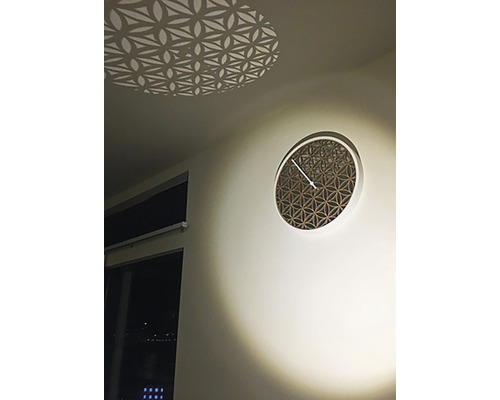 Dekoratívne nástenné hodiny s geometrickým vzorom a svetelným efektom na strope