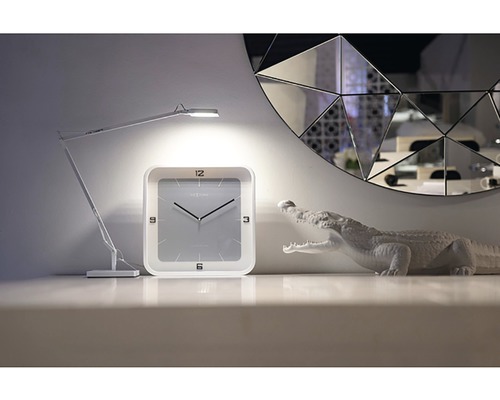 Dekorácia so stolnou lampou, hodinami a figúrkou krokodíla pred zrkadlom