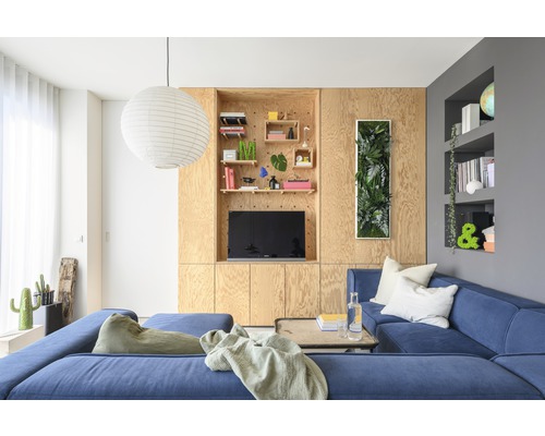 Obývacia izba s modrou rohovou pohovkou, dreveným obkladom a dekoráciami