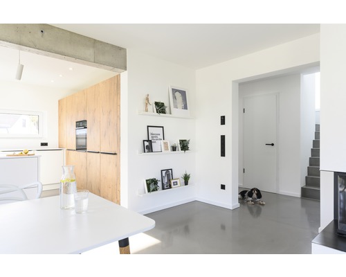 Svetlá obývacia izba s otvorenou kuchyňou, jedálenským stolom a dekoráciou na stene