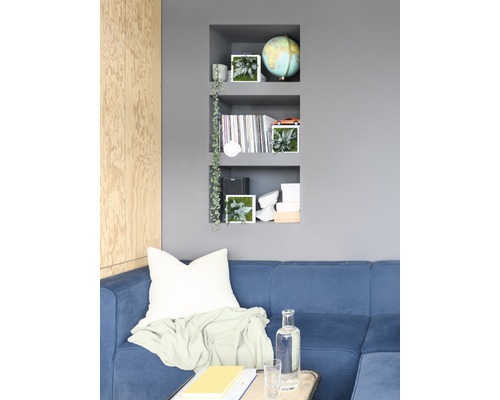 Obývacia izba s modrou pohovkou, nástennou policou a dekoratívnymi prvkami pre dizajn interiéru