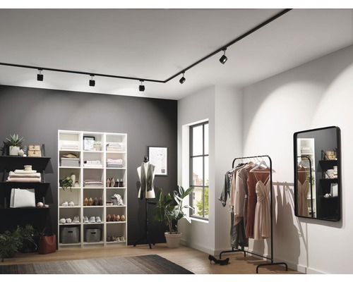 Moderná šatňa s čiernym koľajnicovým osvetlením, regálmi a vešiakom na oblečenie