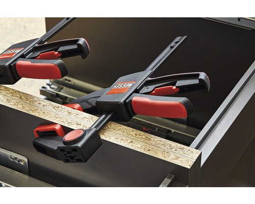 Dve svorky upevňujú obrobok ku skrini.