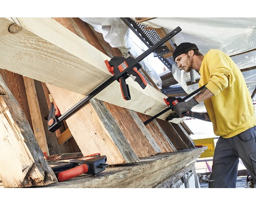 Muž upevňuje drevo pomocou pákovej svorky