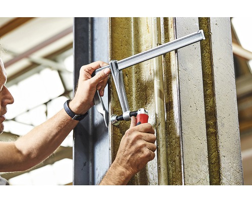 Osoba upevňuje zverák na nosník.