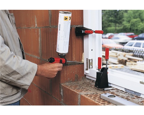 Remeselník utesňuje okno penovou pištoľou