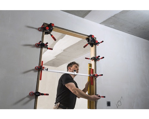 Muž montuje zárubňu pomocou zarovnávacích svoriek